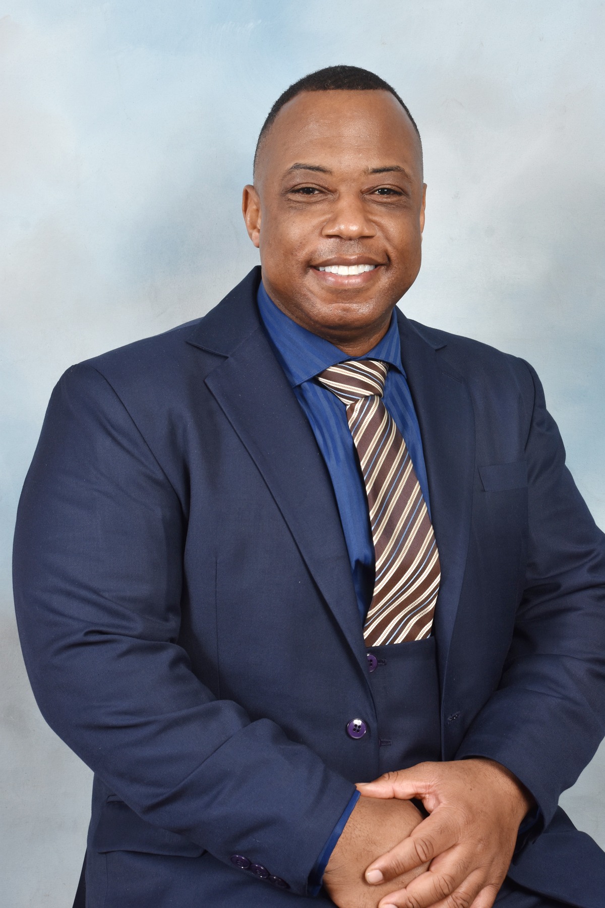 A Black Man in a Suit and Tie Seated on a Chair, Exuding Professionalism and Confidence.