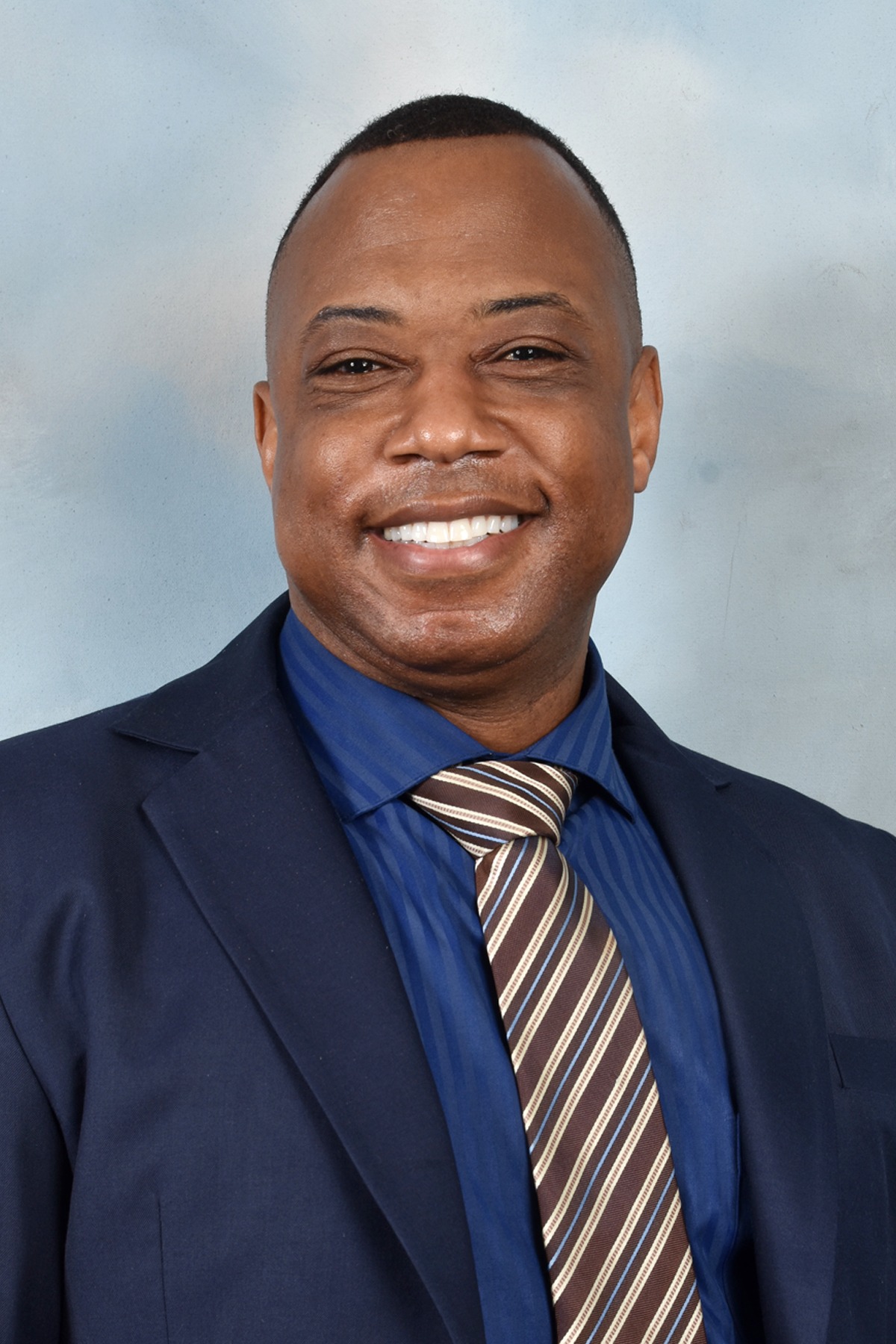 A Man in a Suit and Tie Smiling Warmly at the Camera.