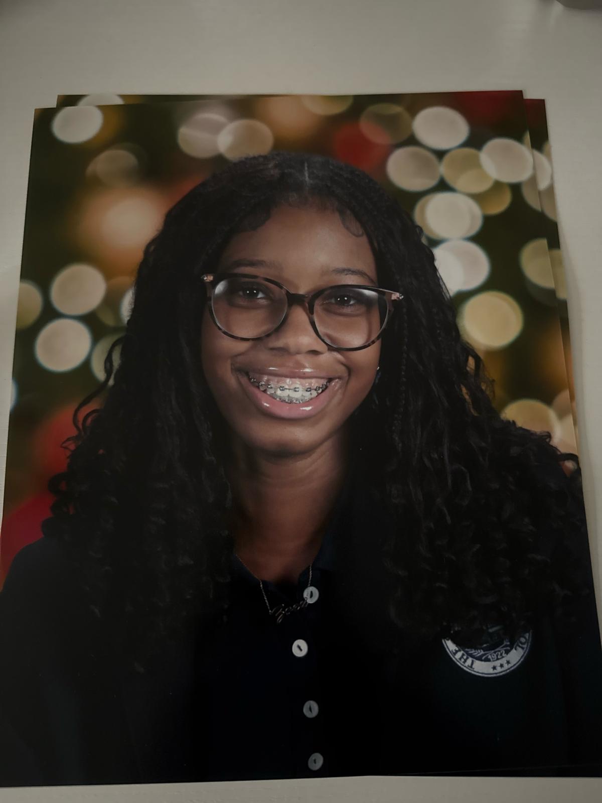 A Young Woman Wearing Glasses Smiles at the Camera, Showcasing Her Casual Style and Friendly Demeanor.